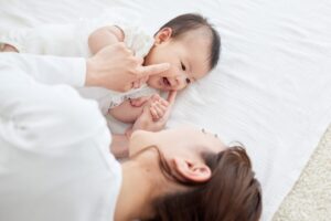 ベビーマッサージをする笑顔の赤ちゃんとママ