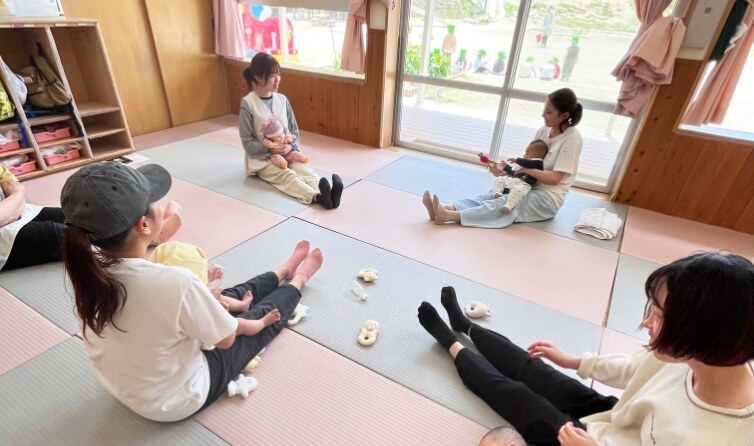 赤ちゃんを膝に乗せ向き合う母親たち